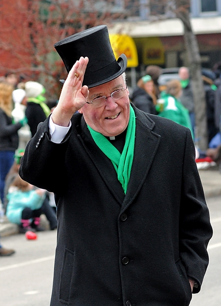 Bishop Richard Malone walks north on Delaware Avenue as he waves to St. Patrick's Day Parade attendees as they sing 